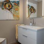 Badezimmer mit Waschbecken, Spiegel und Wandbild