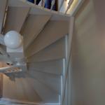 Spiralstiege mit weißer Balustrade und farbigem Bild an der Wand.
