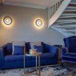 Ein Wohnzimmer mit blauem Sofa, Sessel und einer Treppe.