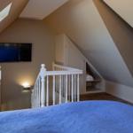 Schlafzimmer mit Dachschrägen, Bett, Fernseher und kleinem Treppenaufgang.