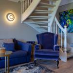 Ein Wohnzimmer mit blauer Couch, einem Sessel und einer Treppe.