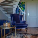 Eingangsbereich mit blauer Sitzgelegenheit, Treppe und Wandbild.