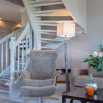 Eine Wohnzimmer-Ecke mit Sessel, Tisch und Treppe.