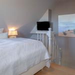 Schlafzimmer mit Bett, Lampe und Fernseher an der Wand.