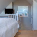 Schlafzimmer mit Dachschräge, Bett, Fernseher und Wandbild