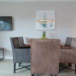 Esszimmer mit Holztisch, vier Stühlen und Wand-TV. Deckenleuchte und Stehlampe sorgen für Beleuchtung.
