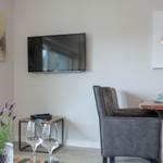 Wohn- und Essbereich mit Fernseher, Tisch und Stühlen sowie Wandbildern.