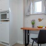 Küche mit Mikrowelle und Arbeitsplatz mit Tisch, Stuhl und Fenster.