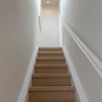 Treppe mit Teppichstufen führt nach oben. Deckenfenster sorgt für Licht.