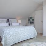 Schlafzimmer mit Doppelbett, weißen Nachttischen und Kleiderschrank unter schrägem Dach.