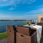 Terrasse mit Sitzgelegenheiten und Blick auf Wasser und Hafen.