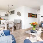 Wohn- und Küchenbereich mit Holzboden, Sofa, Esstisch und Küchengeräten.