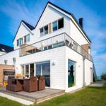 Modernes Haus mit Balkon und Terrasse mit Gartenmöbeln. Blick auf den Himmel.