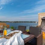 Terrasse mit Tisch, Stühlen und Liege am Wasser