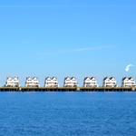 Row of white houses along a waterfront under a blue sky.