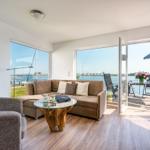 Living room with water view, sofa, table, and terrace with seating.