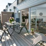 Deck with table and chairs, view of water and kitchen area.