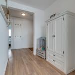 Hallway with wooden floor, white wardrobe, and coat hooks on the wall.