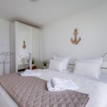 Bedroom with double bed, mirrored wardrobe, and standing lamp. Wall decor with anchor.