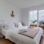 Bedroom with bed, window view, and wooden floor.