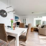 Dining area with table and chairs, living area with sofa and windows