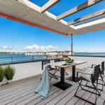Terrasse mit Tisch, Stühlen und Blick auf Wasser und Häuser.