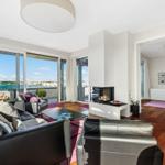 Wohnung mit Blick auf Wasser, Kamin und Schlafzimmer im Hintergrund.