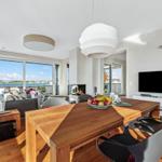 Modernes Wohn- und Esszimmer mit Blick auf Wasser. Esstisch mit Stühlen und Fernseher.