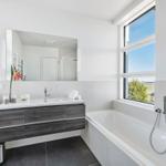 Badezimmer mit Badewanne, Dusche und Waschbecken mit Spiegel.