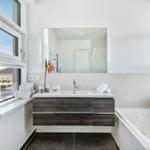 Badezimmer mit Waschtisch, Badewanne und Fenstern.