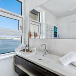 Badezimmer mit Blick auf Wasser und Himmel durch großes Fenster.