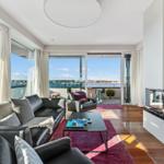 Wohnzimmer mit Sofa, Kamin und Blick auf Hafen