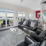 Wohnzimmer mit Sofa, Sessel und Blick aufs Meer.
