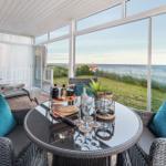 Terrasse mit Sitzgruppe und Tisch. Blick auf das Meer und Grasland.