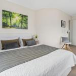 Schlafzimmer mit Bett, Wandbild und Holzboden