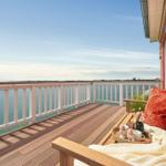 Terrasse mit Blick auf das Meer und Holzbank mit Kissen und Decke.