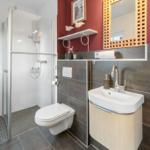 Badezimmer mit Dusche, Toilette und Waschbecken mit Spiegel.