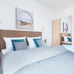 Schlafzimmer mit Bett, Wandbild und Spiegelschrank.