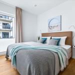 Schlafzimmer mit Bett, Wandbild und Fenster zur Aussicht.