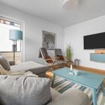 Wohnzimmer mit Sofa, Fernseher und Holzboden.