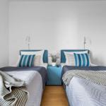 Zwei Einzelbetten mit blauen Kopfteil und Nachttisch in einem Schlafzimmer.