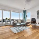 Wohnzimmer mit Sofa, zwei Sessel und Terrasse mit Meerblick.