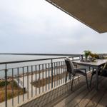 Terrasse mit Tisch und Stühlen überblickt die Küste und den Hafen.