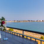 Balkon mit Blick auf das Meer und Ferienhäuser am Ufer.