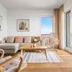 Wohnzimmer mit Sofa, Kamin und Blick aufs Wasser