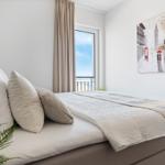 Schlafzimmer mit Bett, Fenster und Wandbild.