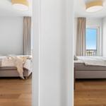 Schlafzimmer mit Bett, Vorhängen und Fensterblick auf Balkon