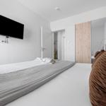Schlafzimmer mit Bett, Fernseher und Spiegeltüren.