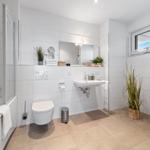 Badezimmer mit Badewanne, Dusche, Waschmaschine und Pflanzen.