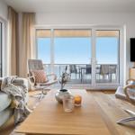Wohnzimmer mit Blick auf den Balkon und Meer. Möbel und Dekoration sind modern.